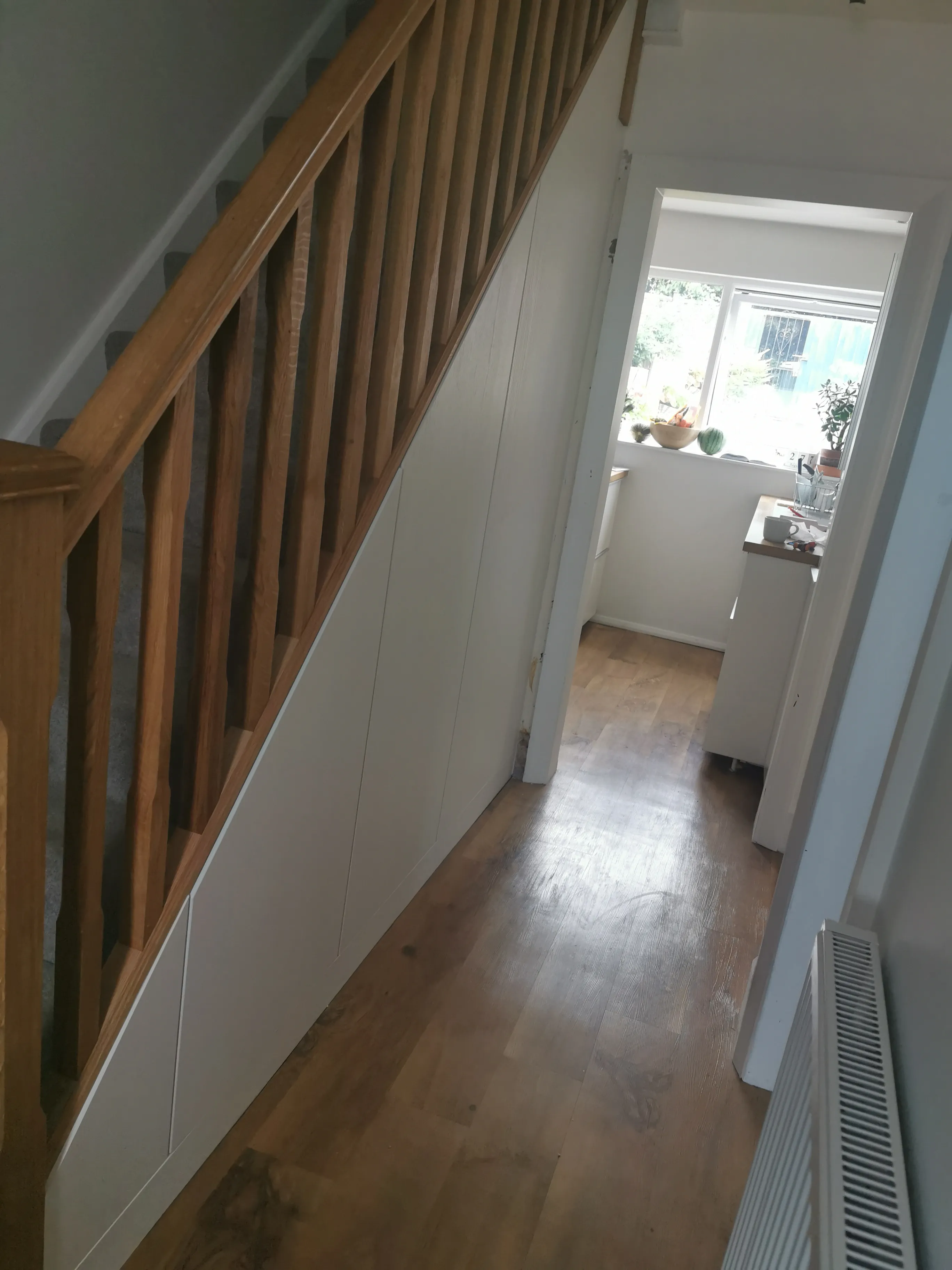 Textured white under stairs doors with push to open latches beneath an oak balustrade