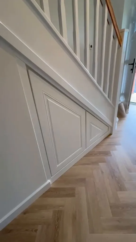 White panelled under stairs frontage, closed, above herringbone flooring