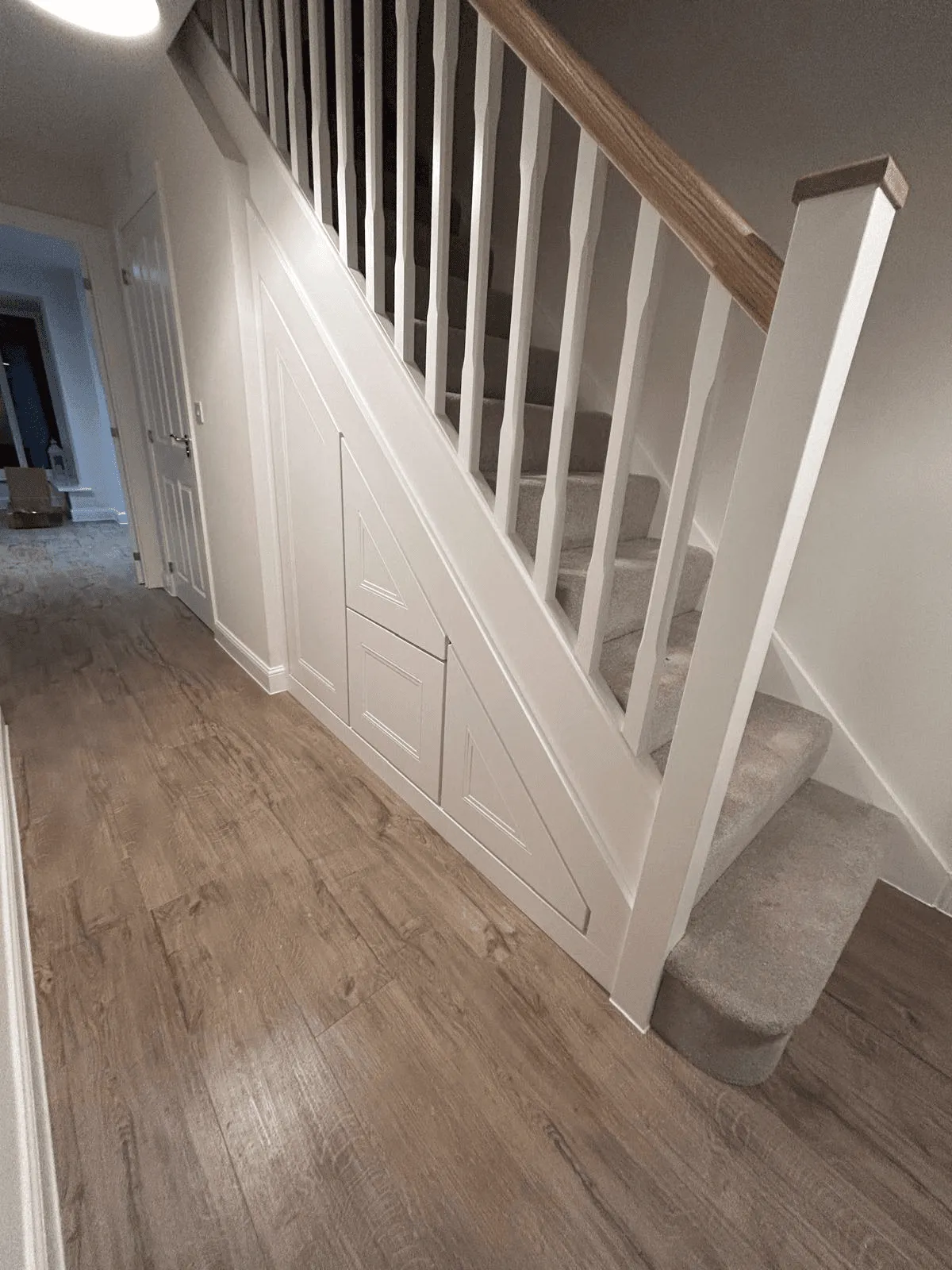 Hallway under stairs storage with panelled doors and drawer in white