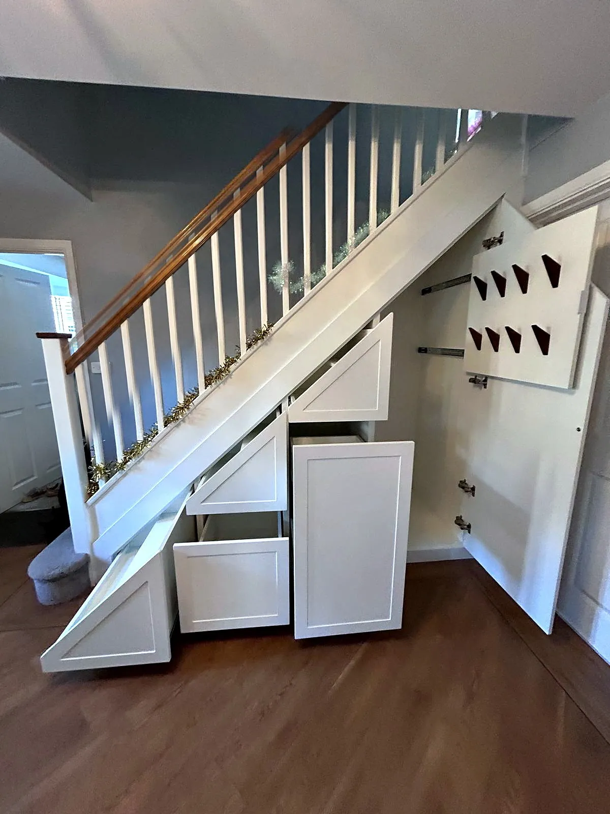 Tall bay open showing a row of coat hooks, with a drawer pulled out below