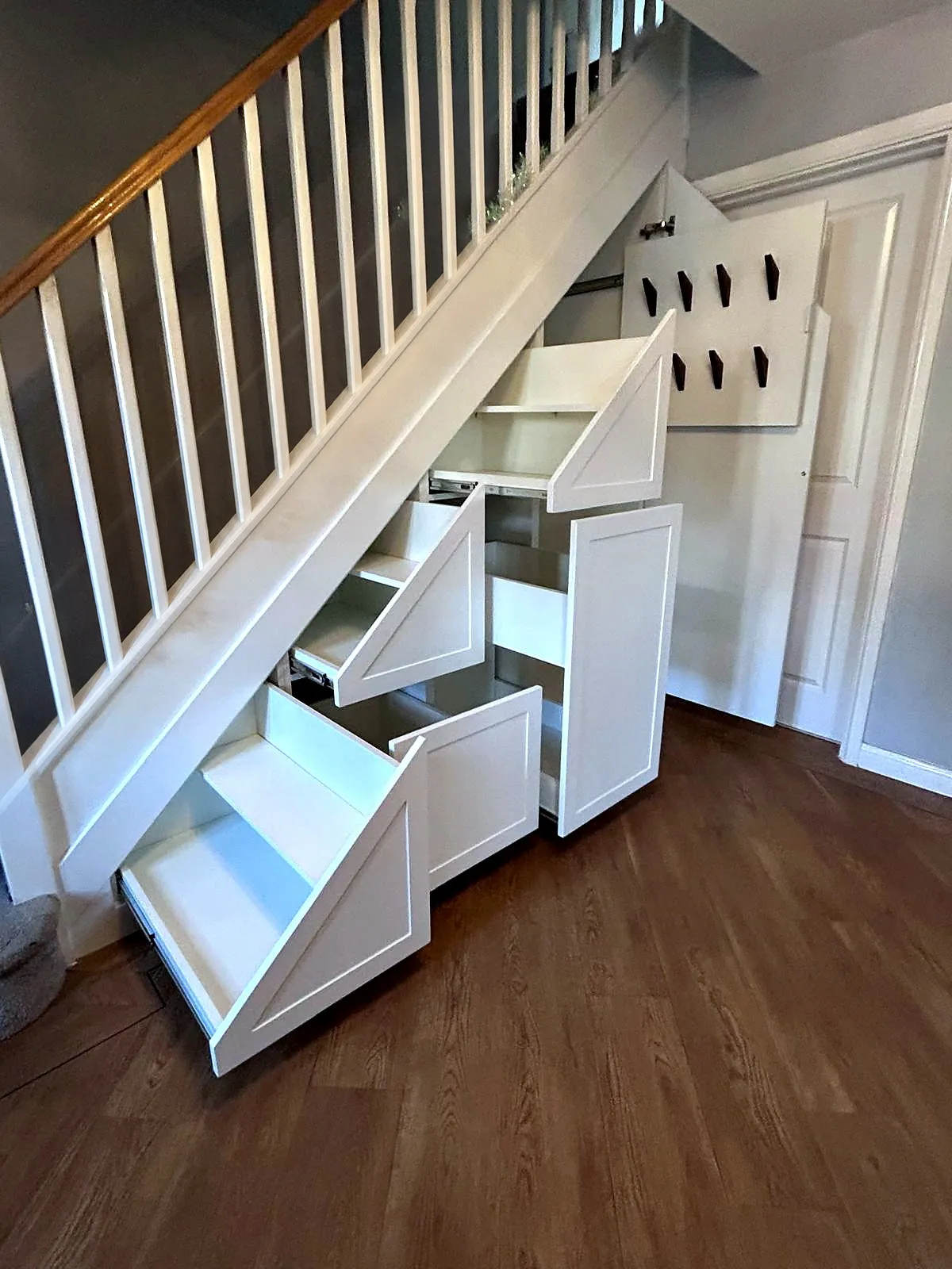 White Shaker under stairs storage with three pull out drawers open at different depths